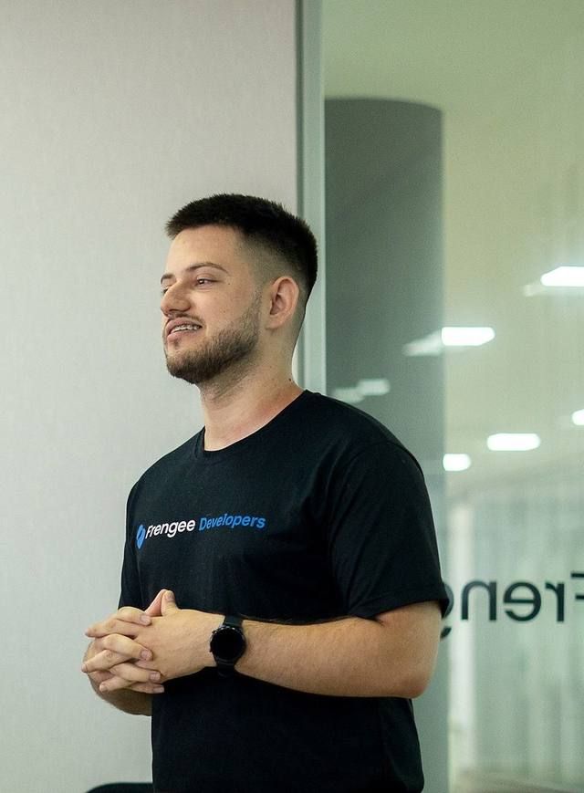 Bruno Cardozo standing in a glass-walled office at Frengee, hands clasped, mid-presentation